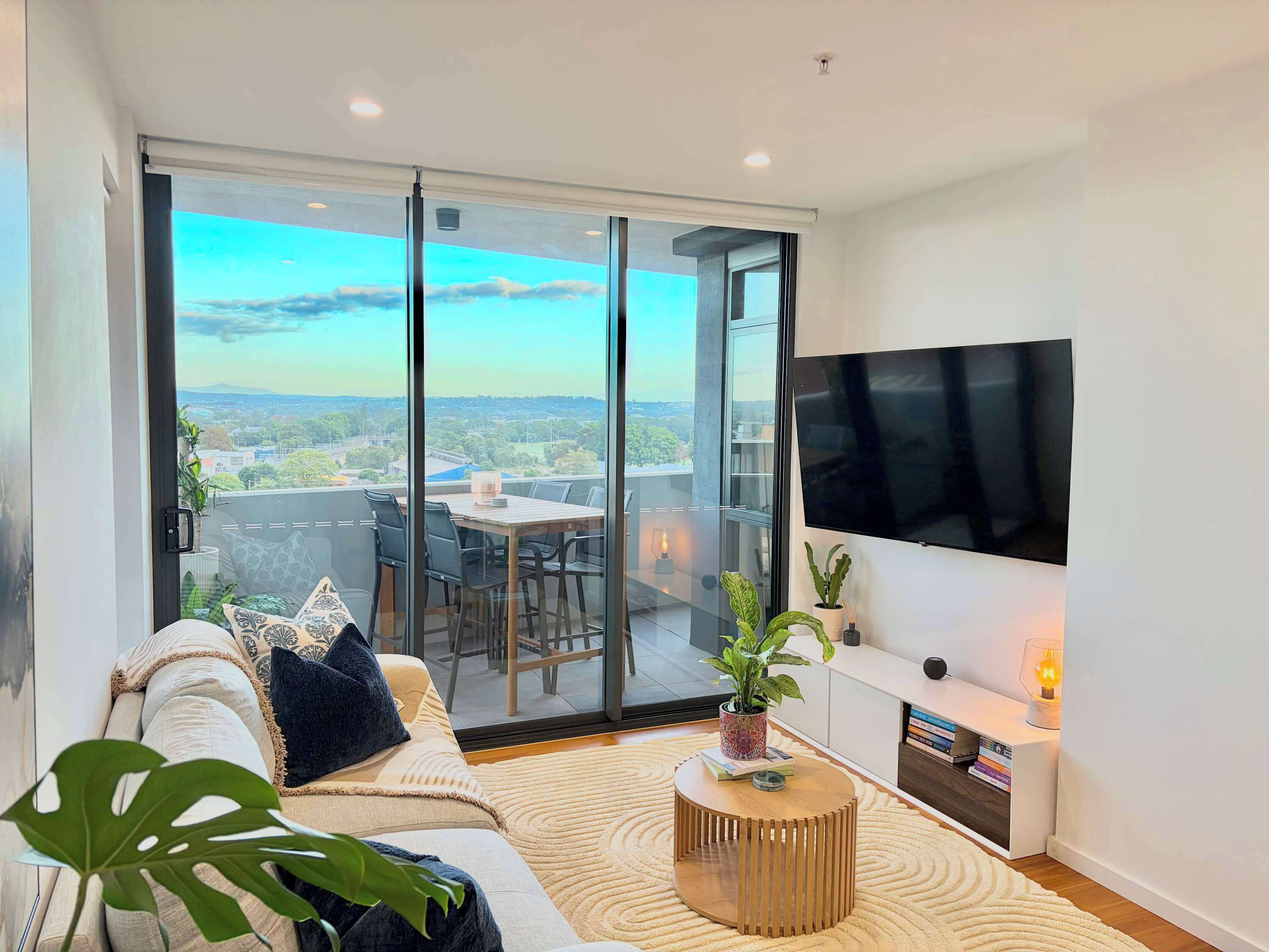 A modern living room with a sofa, coffee table, and a TV mounted on the wall.