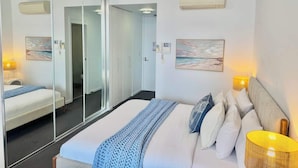 Een moderne hotelkamer met een groot bed, een glazen scheiding en kunstwerken aan de muren.