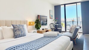 Een moderne hotelkamer met een groot bed, een bureau, een stoel en uitzicht op de stad.