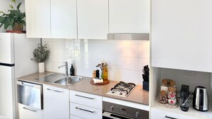Een moderne keuken met witte kastjes, roestvrijstalen apparatuur en een gasfornuis.