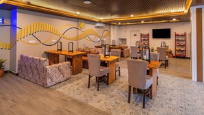 A modern interior with a wooden ceiling, patterned floor, and a seating area with tables and chairs. - The Hosteller Bam Bir (Jogindarnagar)