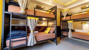 A bunk bed room with curtains, a ceiling fan, and a light fixture. - The Hosteller Bam Bir (Jogindarnagar)