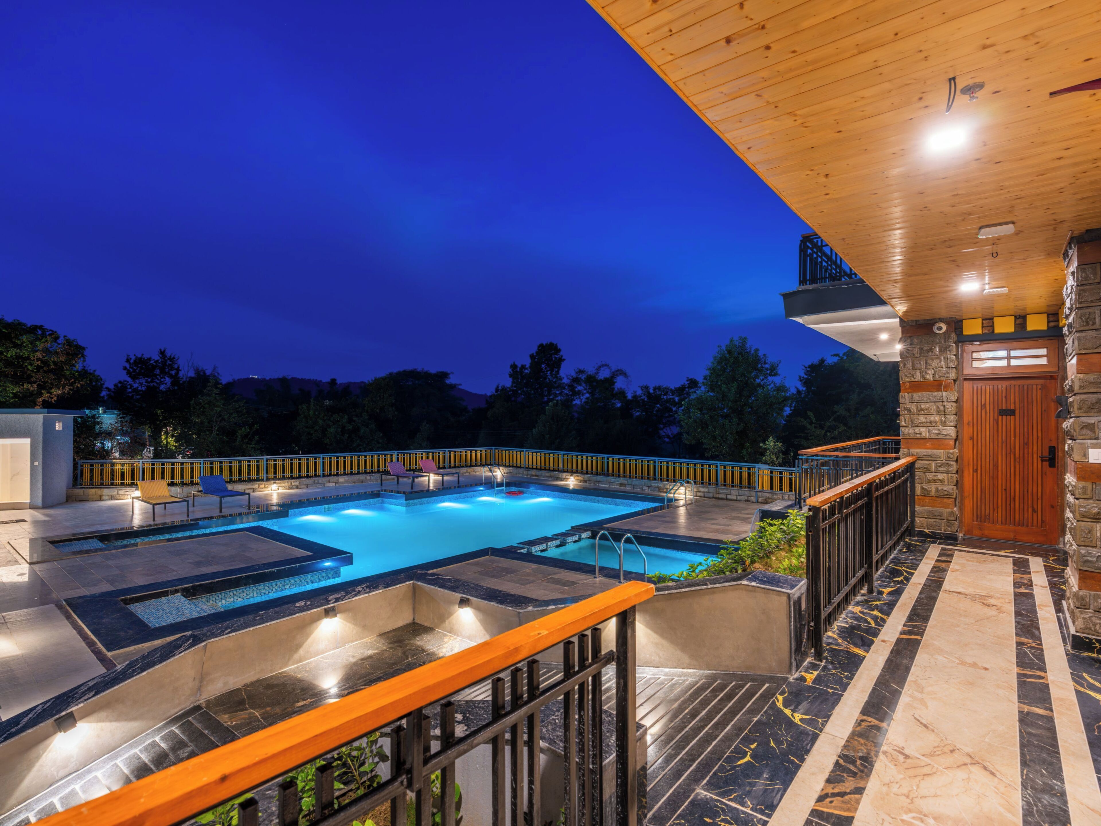 A swimming pool with a wooden deck and a stone wall.