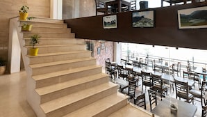 Un interior moderno con una escalera, una zona de bar y un comedor con mesas y sillas.