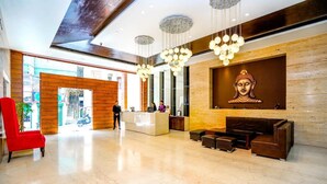 Un vestíbulo de hotel con mostrador de recepción, zona de estar y una estatua de Buda en la pared.