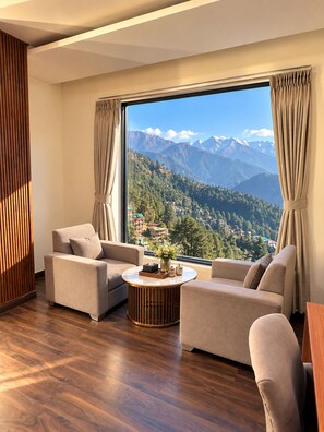 Ein modernes Wohnzimmer mit großem Fenster und Blick auf die Berge, zwei Sofas, einem Couchtisch und Holzböden.