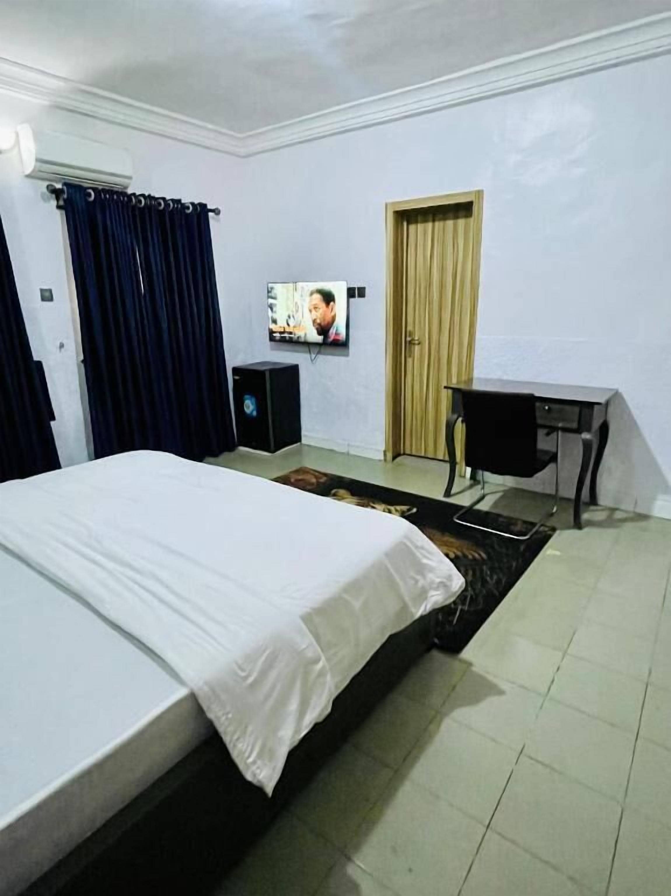 A hotel room with a bed, a desk, a TV, and a wardrobe.