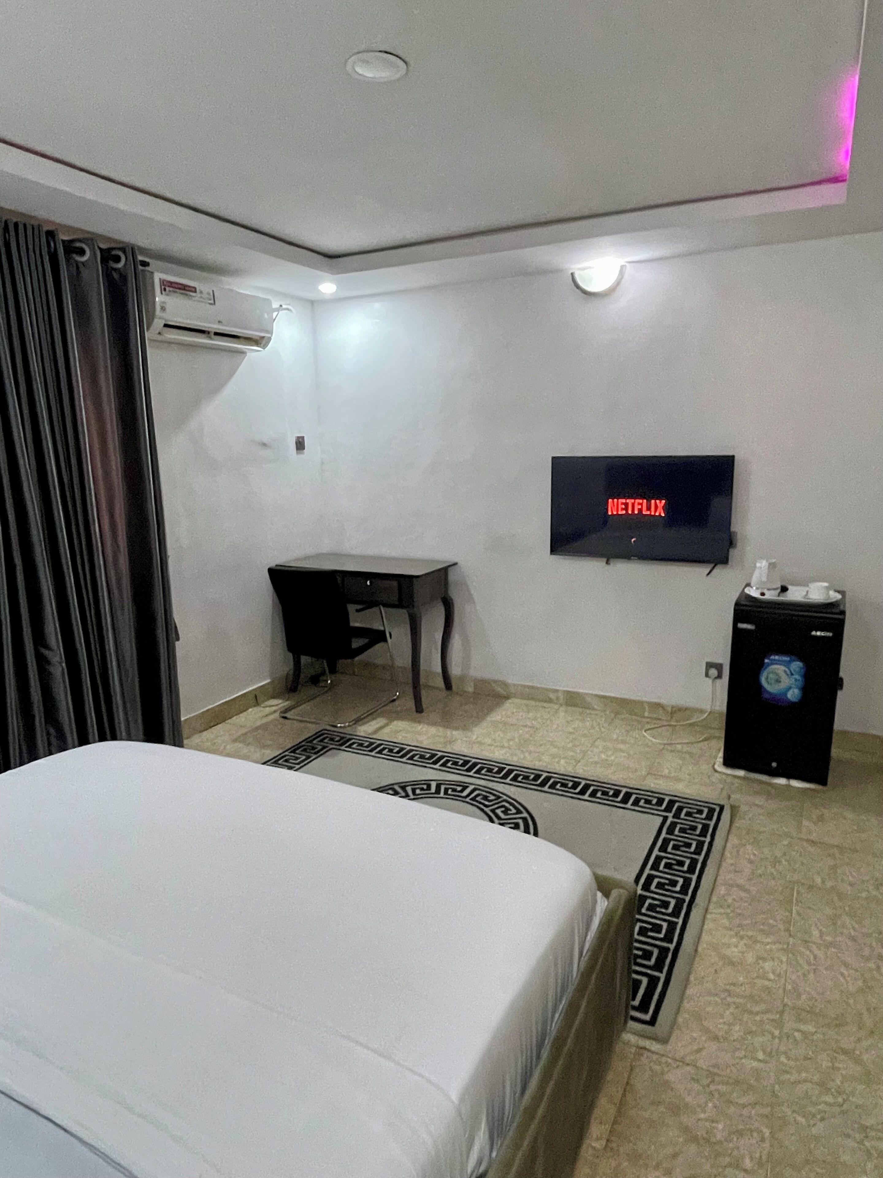 Une chambre d’hôtel équipée d’un lit, d’un bureau, d’un téléviseur fixé au mur et d’un appareil de climatisation.