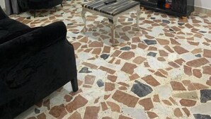A living room with a flat-screen TV, a black sofa, a black armchair, a coffee table, and a patterned floor. - Weena Hotel & Resort (Lekki)