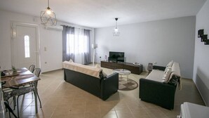 Una sala de estar moderna con un sofá, una mesa de centro, un televisor y un comedor con sillas y una mesa.