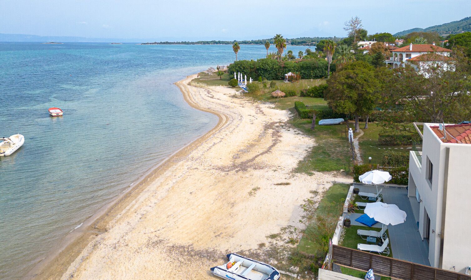A coastal hotel with a beach view, a pool area, and a garden.