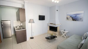 Un espacio habitable compacto con kitchenette, chimenea, mesa de comedor y sofá.