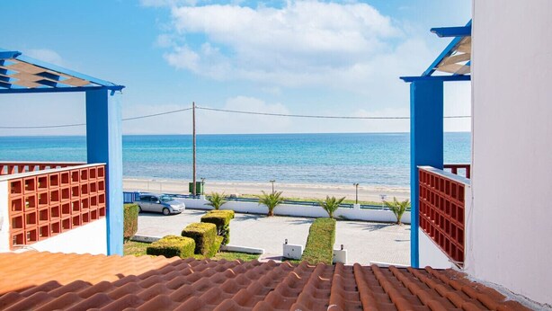 Vista desde un balcón hacia una playa bajo un cielo despejado.