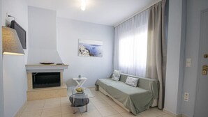 Een moderne woonkamer met een open haard, een bank, een tafeltje en een schilderij aan de muur.