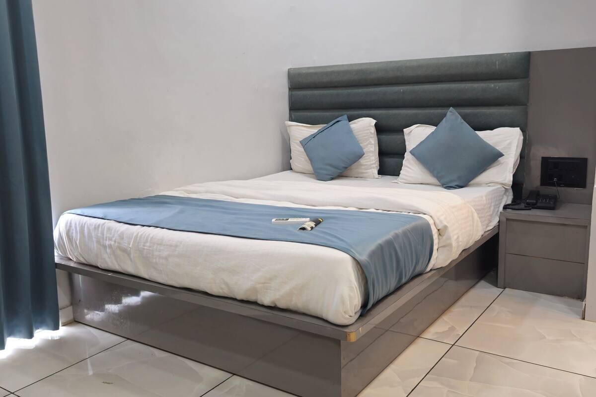 Quarto moderno com cama, mesa de cabeceira e espelho.