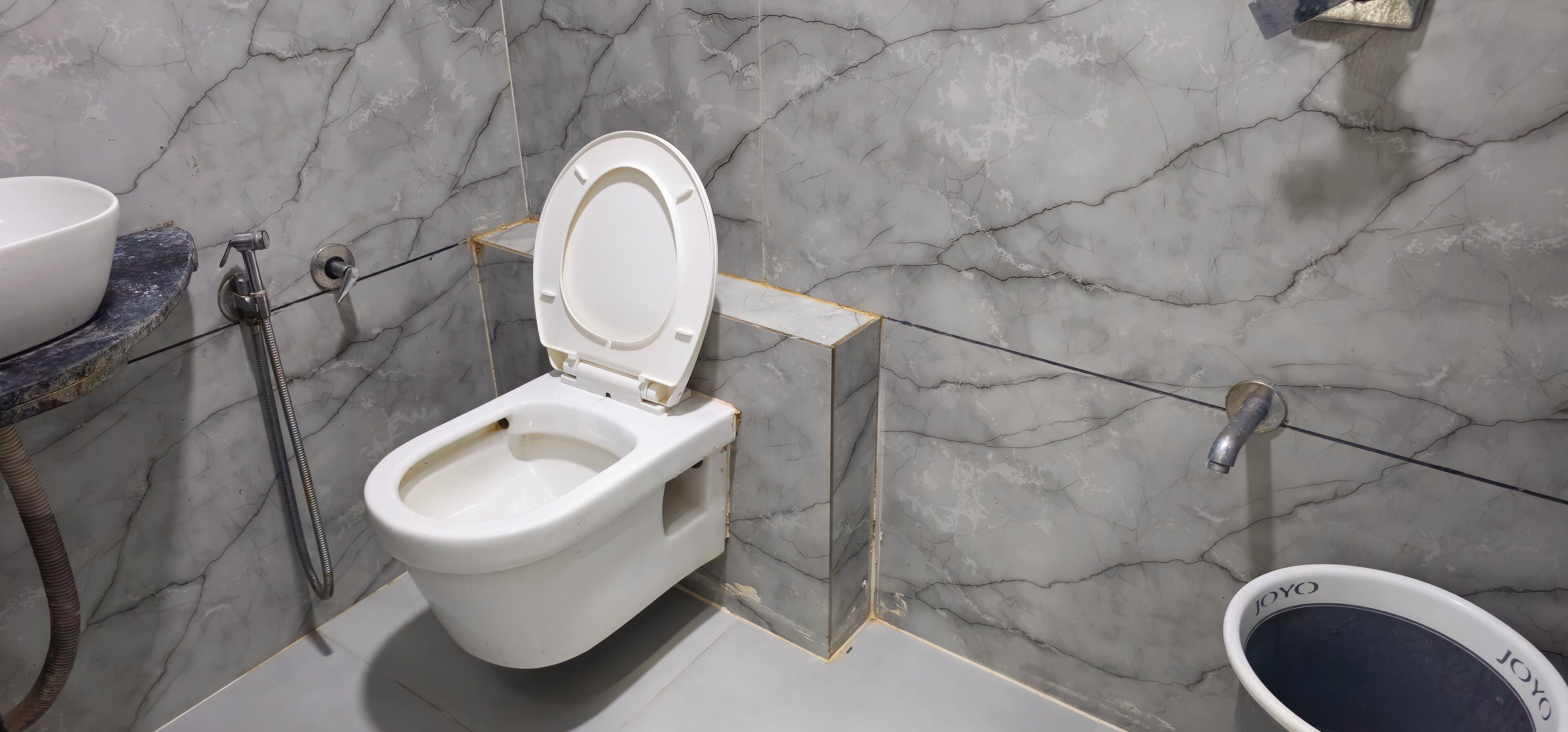 Des toilettes équipées d’un accessoire bidet, d’un siège-bidet et d’un tuyau de bidet.