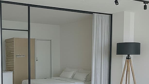 Un dormitorio con cama, puerta corrediza, lámpara y espejo.