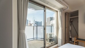 A hotel room with a large sliding glass door to a balcony, a bed, a chair, and a desk. - ESLEAD HOTEL Namba East (Osaka)