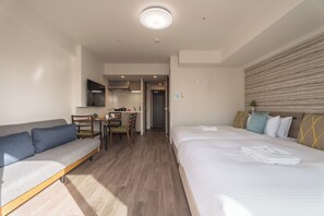 Camera d'albergo con divano, letto, zona pranzo e cucina.