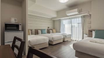 Een hotelkamer met twee bedden, een eettafel, een magnetron en een airconditioner.