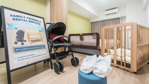 A family-friendly rental service room with a crib, a stroller, and a sign indicating availability for rent. - ESLEAD HOTEL Namba East (Osaka)