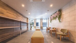 A modern lobby with a long bench, seating area, and a reception desk. - ESLEAD HOTEL Namba East (Osaka)