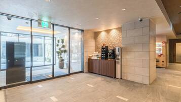 Eine moderne Lobby mit einer Rezeption, einer Kaffeemaschine und einem großen Fenster.
