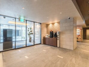 A modern lobby with a reception desk, a coffee machine, and a large window. - ESLEAD HOTEL Namba East (Osaka)