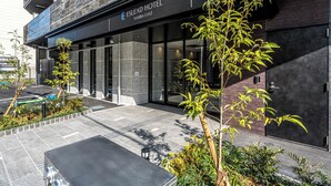 The exterior of the Eslead Hotel with a modern facade, large glass windows, and a small outdoor seating area. - ESLEAD HOTEL Namba East (Osaka)
