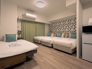 Een hotelkamer met een bed, twee eenpersoonsbedden, een flatscreen-tv, een minibar en een wandairco.