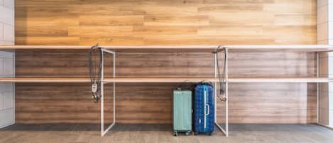 A room with a wooden wall, a metal shelf unit, and two suitcases on the floor.