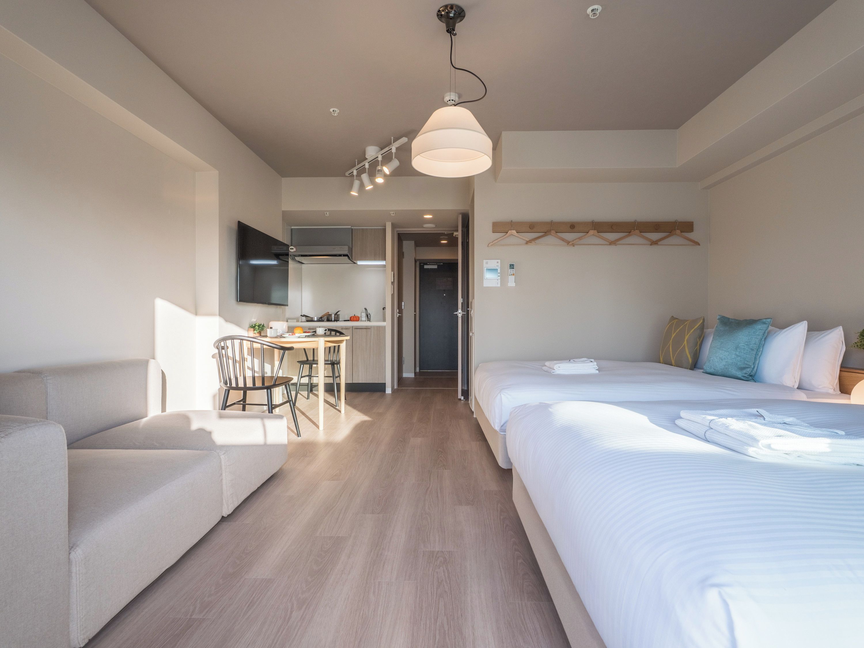 A hotel room with a bed, a sofa, a dining area, and a kitchen.