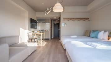 A hotel room with a bed, a sofa, a dining area, and a kitchen.