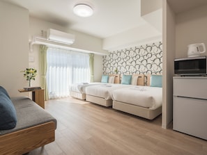 A modern hotel room with a sofa, two beds with matching headboards, a small table with a vase, and a kitchenette. - ESLEAD HOTEL Namba East (Osaka)