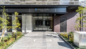The entrance to the Eslead Hotel with a clear pathway, a signboard, and a modern building facade. - ESLEAD HOTEL Namba East (Osaka)