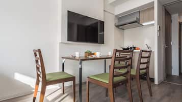 Una cocina compacta con zona de comedor, que incluye una mesa, sillas y un televisor.