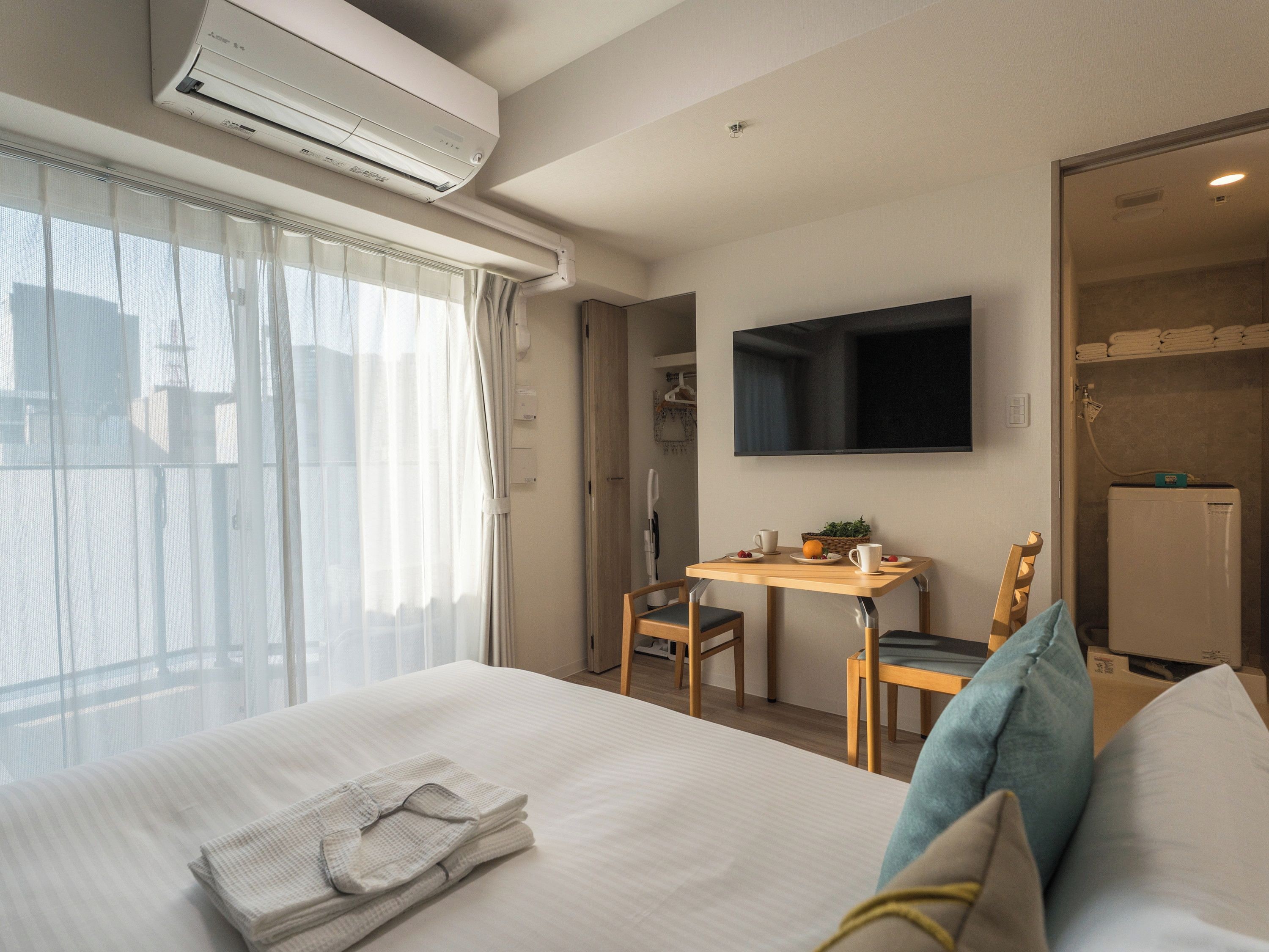 Ein Hotelzimmer mit Bett, Schreibtisch, Stuhl, Flachbildfernseher und einer Duschkabine.
