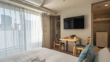 Ein Hotelzimmer mit Bett, Schreibtisch, Stuhl, Flachbildfernseher und einer Duschkabine.