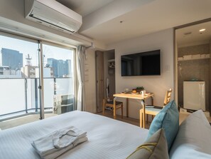 Een hotelkamer met een bed, een bureau, een stoel, een televisie en uitzicht op de stad.