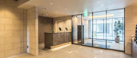 A reception area with a reception desk, a wall-mounted security camera, and a glass door leading to the outside.