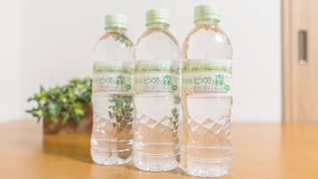 Three bottles of water with labels on a wooden table against a plain background.