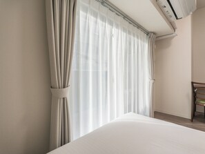 A hotel room with a bed, a chair, and a window with sheer curtains. - ESLEAD HOTEL Namba East (Osaka)