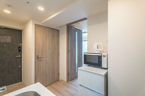 Eine kleine Küche mit Mikrowelle, Kühlschrank und einer Holztür.