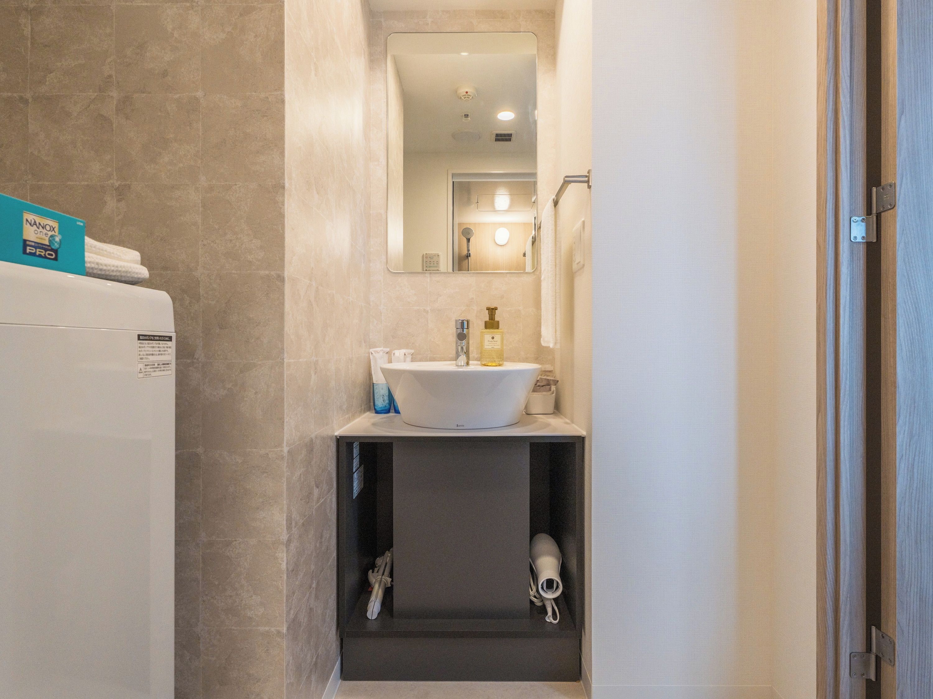 Une petite salle de bain avec un lavabo blanc, un miroir et un porte-serviettes.