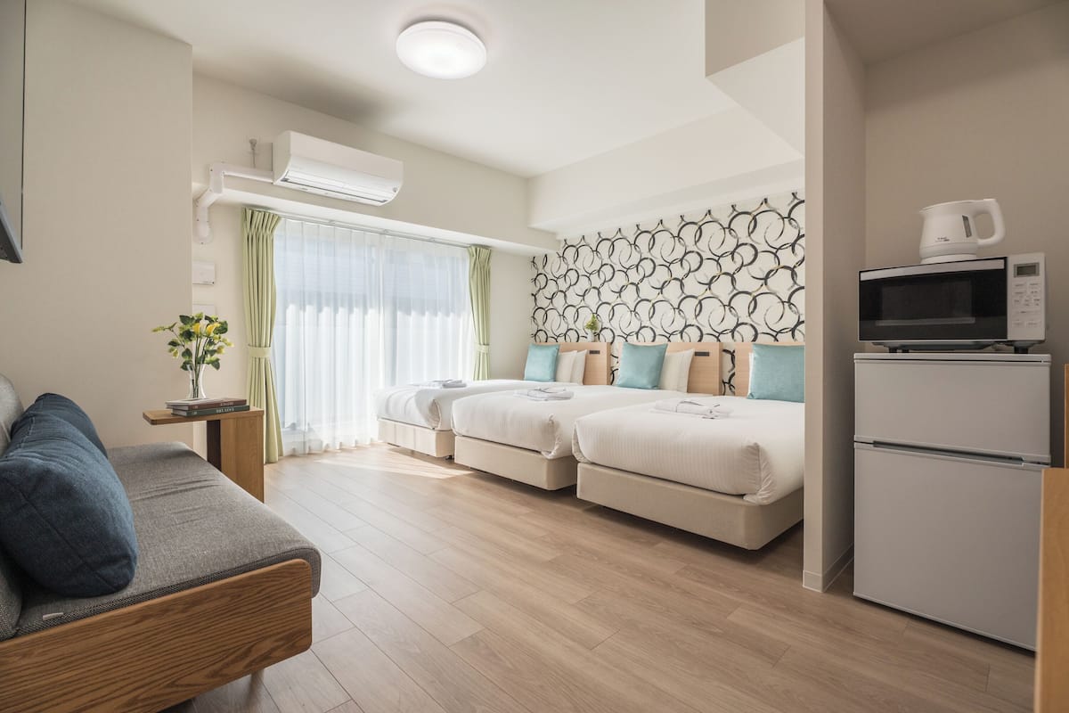 Une chambre moderne équipée d’un canapé, de deux lits, d’un four à micro-ondes et d’un appareil de climatisation.