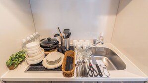 Un piano di lavoro in cucina con piatti e ciotole impilati, un cesto di utensili e un lavandino.