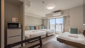 Una camera d'albergo con un letto, una scrivania con un forno a microonde, una sedia, una finestra con tende e un condizionatore d'aria.