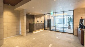 A modern lobby with a reception desk, a glass door entrance, and a coffee machine. - ESLEAD HOTEL Namba East (Osaka)