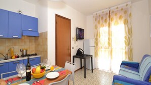 A compact living space with a kitchenette, a dining area, and a sofa. - Comfy Flat With Shared Swimming Pool (San Michele al Tagliamento)
