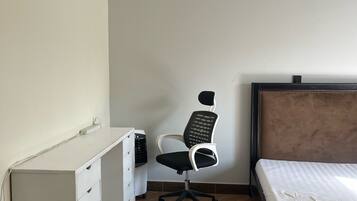 A bedroom with a bed, a desk, a chair, and a fluffy rug.